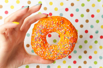 Woman holding delicious donut on color  background
