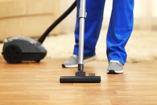Close up of man hoovering floor with vacuum cleaner