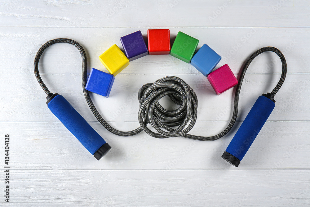 Wall mural Skipping rope and cubes with space for text on wooden background