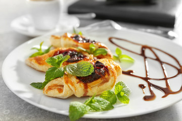 Plate with sweet tasty pastries on light background