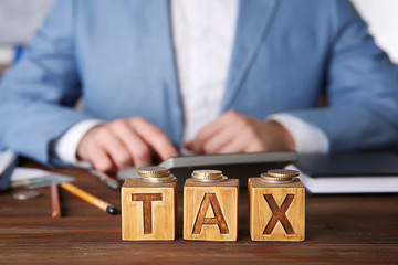 Wooden cubes with word TAX on table