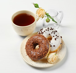 Plate with delicious donuts, cup of coffee and flower on white background