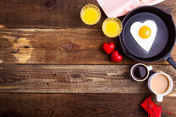 Heart shape fried egg, fresh orange juice and coffee. Top view