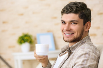 Handsome young man drinking coffee at home