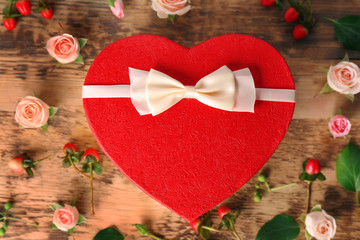 Heart shaped gift box with flowers on wooden background