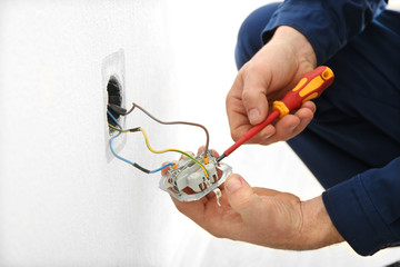 Electrician disassembling wall socket in new building, closeup