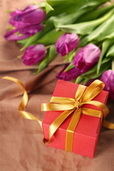 Gift box with tulips on fabric background