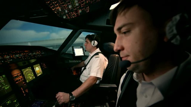 Side view of Airbus A319 A320 A321 cabin. Captain and co-pilot perform radio communication with tower of airport before turn on power of engines of aircraft. Ready to take off and departure.