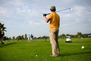 Business man holding golf club playing on grass field background. Active male outdoors