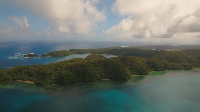Aerial view tropical island with the mountains and the rainforest on a background of ocean. Aerial footage, sea and the tropical island with rocks, beach and waves. Seascape: sky, clouds, rocks, ocean