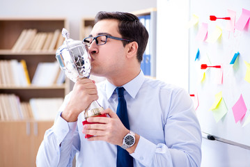 Young businessman receiving prize cup in office