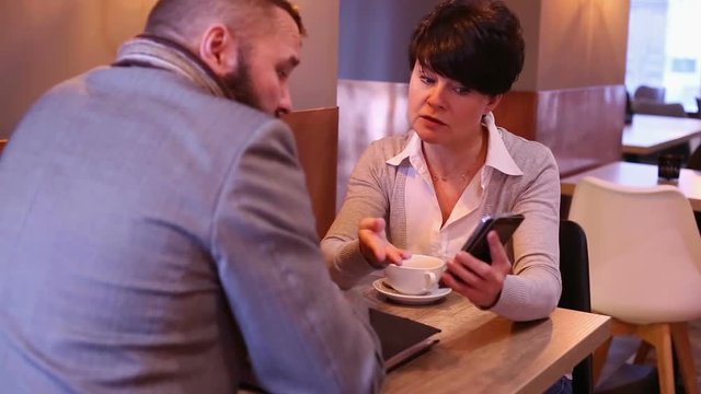 Couple businesspeople with cellphone talking in cafe

