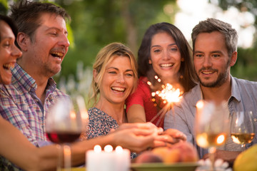 A group of friends having fun outdoors, they hold spark sticks