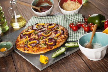 Tasty pizza, tomatoes and others ingredients on a wooden backgro