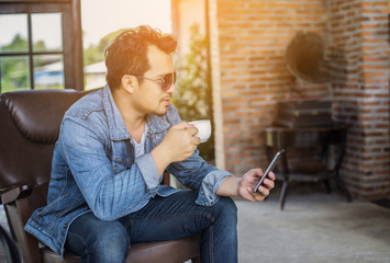 Businessman hands using cell phone with laptop at office desk.