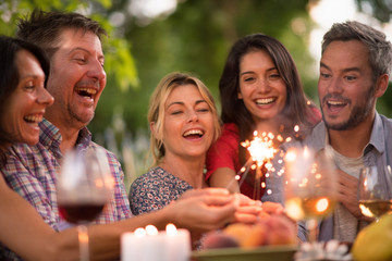 A group of friends having fun outdoors, they hold spark sticks