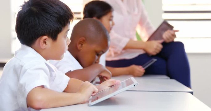 School kids and teacher using digital tablet in classroom at school 4k