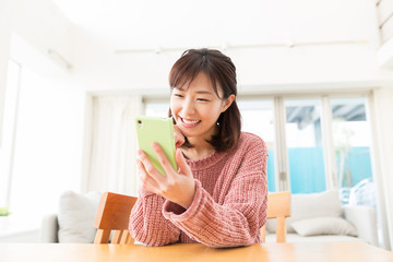 部屋でスマホを見る女性