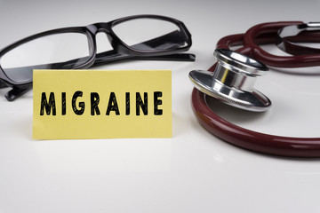 Sticky notes written with MIGRAINE and stethoscope on white background. Medical Concept.