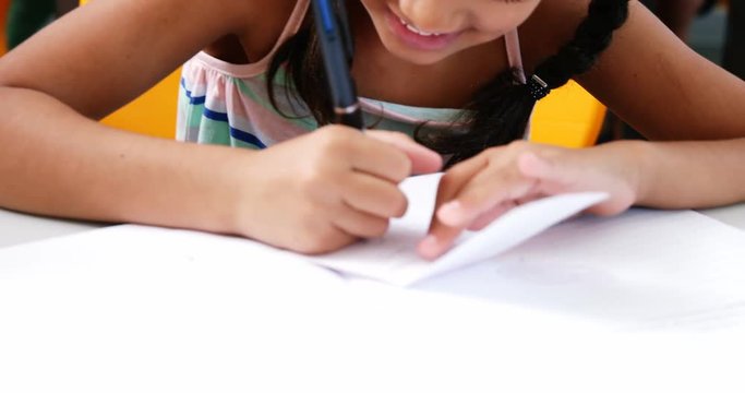 Schoolgirl writing on chit in classroom at school 4k