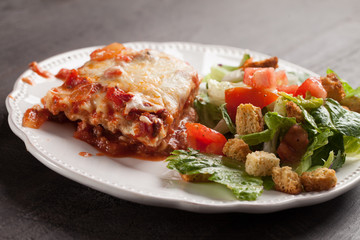 Homemade Italian four cheese lasagna with a side salad horizontal shot