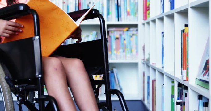 Slow motion of disabled school girl reading book in library at school 4k