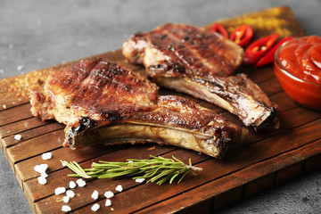 Grilled meat with sauce and chili pepper on cutting board, closeup