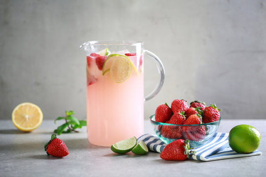 Jug with fresh berry and citrus cocktail on table