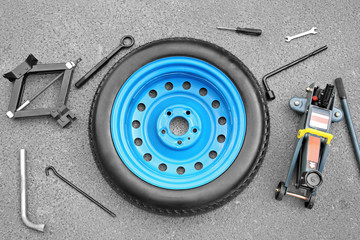 Car wheel with tools on asphalt background