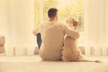 Handsome man with cute dog at home