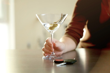 Woman sitting at table with glass of alcoholic beverage and car key, closeup. Don't drink and drive concept