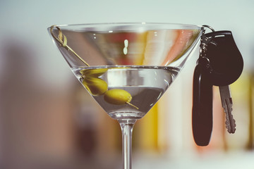 Glass of alcoholic beverage and car key on blurred background, closeup. Don't drink and drive concept