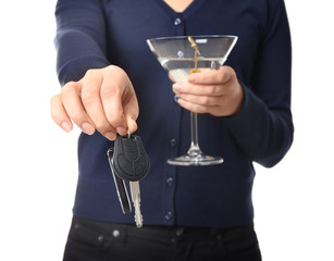 Woman with car key and glass of alcoholic beverage on white background, closeup. Don't drink and drive concept