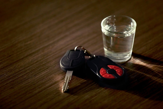 Glass with alcoholic beverage and car key on table. Don't drink and drive concept