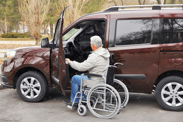 Naklejka premium Man in a wheelchair next to his car