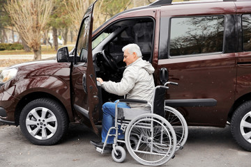 Fototapeta premium Man in a wheelchair next to his car