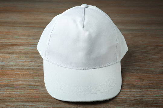 Blank white baseball cap on wooden background