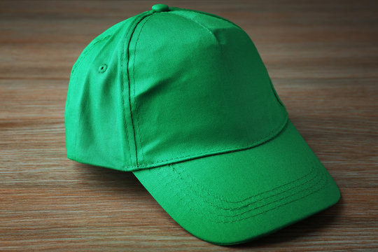 Blank green baseball cap on wooden background