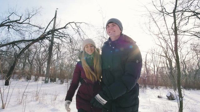 Young couple walking and having fun in snowy park, slow motion