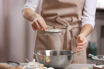 Young woman making dough in kitchen, closeup
