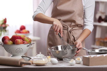 Young woman making dough in kitchen