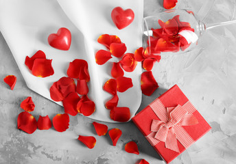 St. Valentines Day concept. Gift box, petals and empty wine glass on table