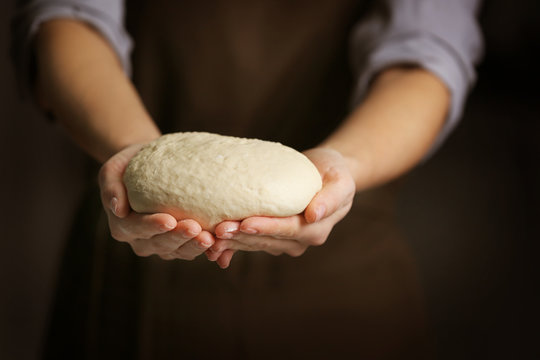 Woman with raw dough in kitchen, closeup