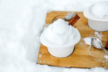 Ice cream cups with snow on wooden board outdoors