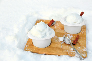 Ice cream cups with snow on wooden board outdoors