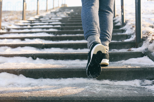 Legs of sportive woman running up stairs in winter, close up view