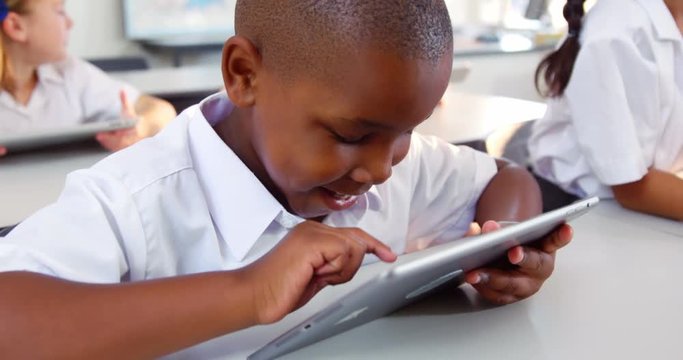 Schoolboy using digital tablet in classroom at school 4k