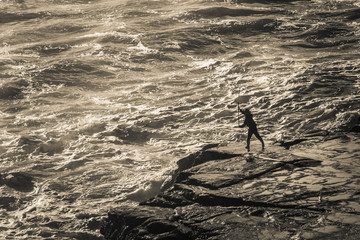 A fisherman braves the wild rocks of west coast New Zealand for