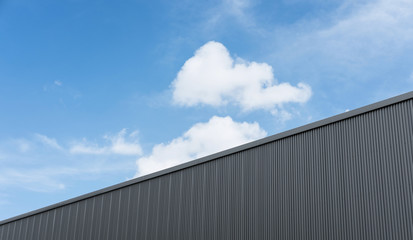 Corrugated factory industry wall on blue sky with clouds 