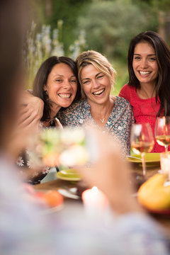 Three beautiful women posing for a photo around a terrace table
